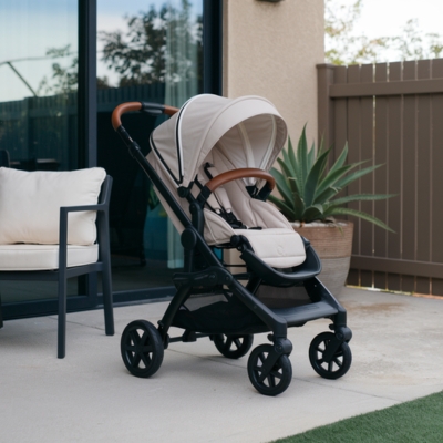 Elegant beige stroller with a leather-accented handle and modern design, set on a patio, perfect for families seeking functionality and style.