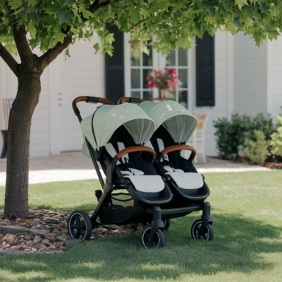 Mint green double stroller with a sleek design and leather-accented handles, set on a lush lawn under a shady tree, ideal for growing families.