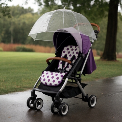 Purple and white polka dot baby stroller with a clear bubble rain cover, positioned on a wet park pathway, providing waterproof protection for infants in rainy weather.